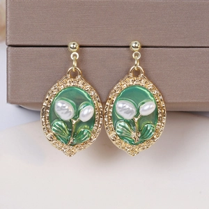 Detail of vintage French style gold earrings with green oil painting base and white pearl
