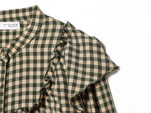 Detail of green gingham shirt featuring ruffled collar and button-down front closure