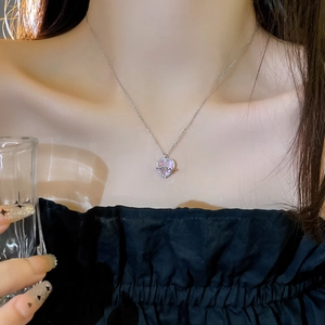 Close-up of pink heart-shaped stone pendant with sparkling butterfly bow on silver chain