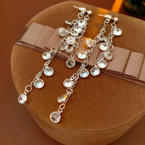 Macro shot of sparkling round cubic zirconia fringe earrings on a brown velvet gift box