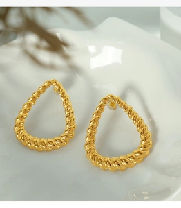 Detailed view of gold-tone teardrop hoop earrings with elegant twisted texture design