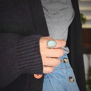 Close-up of vintage oval moonstone ring set paired with a textured silver band on finger