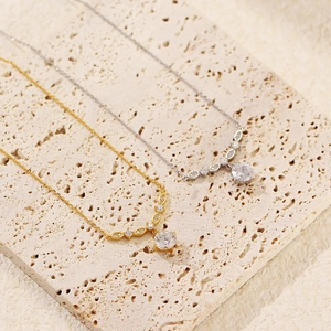 Close-up of gold and silver S925 necklaces with V-shape zircon pendants on stone