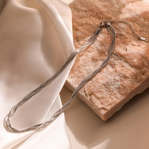 Minimalist silver multilayer chain necklace in stainless steel on white silk
