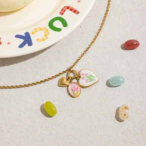 Détail du collier chaîne torsadée dorée 18 carats avec pendentifs fleurs et cœur émaillé