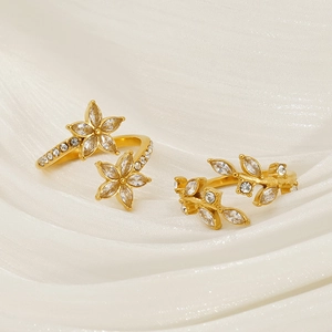 Elegant gold leaf and flower rings with marquise crystals on white silk background