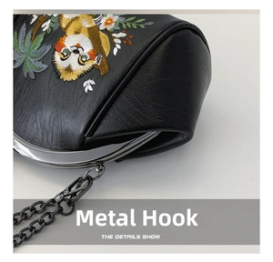 Detail of gun-metal clasp and colorful sloth embroidery on a black leather shell bag