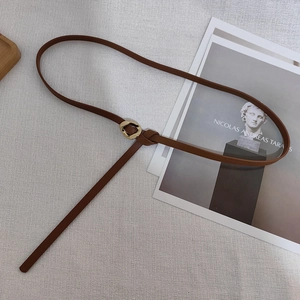Detail of slim brown leather waist chain with artistic irregular gold metal buckle