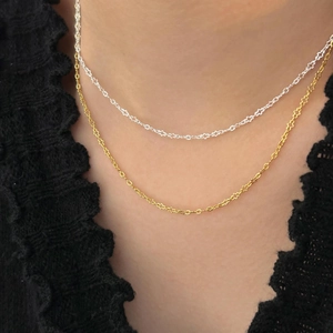 Close-up of minimalist gold and silver layered chains on model with black lace collar