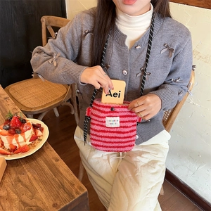 Détail du sac bandoulière pelucheux à rayures roses montrant la texture douce et la corde