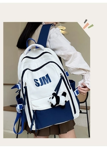 Detailed view of the blue and white backpack featuring SJM logo and panda pendant
