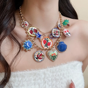 Detail of gold beaded necklace with colorful enamel heart and flower charms on model