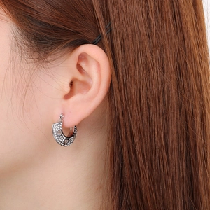 Détail macro de boucles d'oreilles fer à cheval avec cœurs ajourés et oxydes de zirconium