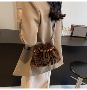Detail of leopard print faux fur bucket bag featuring amber bead clasp and leather strap