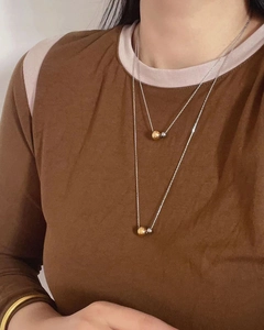 Close-up of double-layered titanium steel necklace with gold and silver bead charms