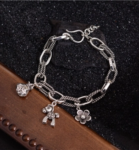 Detail of silver chain bracelet featuring lucky money bag and horse charms