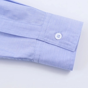 Detailed close-up of light blue striped shirt cuff with stitching and white button