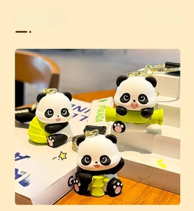 Detailed view of three resin panda charms with bamboo on a wooden desk and ribbon