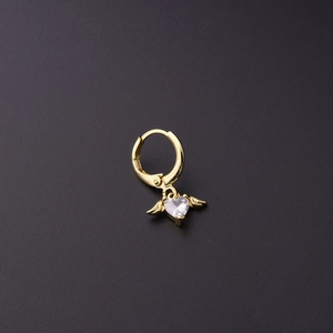 Detail of a golden huggie earring with a heart-shaped zircon and golden angel wings pendant