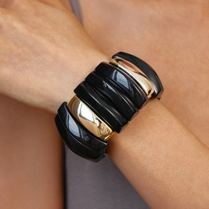Close-up of a wide elastic bracelet with alternating black and gold geometric segments