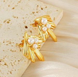Detailed view of vintage gold swallow wings earrings with triple pearls on stone