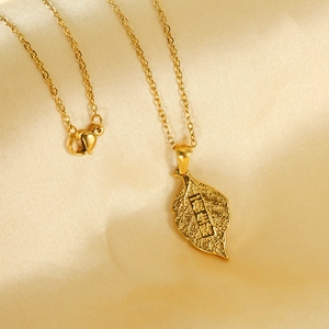 Minimalist gold leaf necklace with engraved wealth blessing on silk background