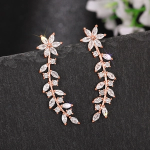 Detail of rose gold flower earrings with marquise-cut white zircons on dark rock