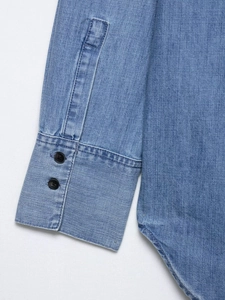 Detail of the dual-button cuffs and hem on this classic blue denim shirt for women