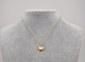 Détail d'un collier pendentif cœur doré minimaliste sur un buste à bijoux en velours gris
