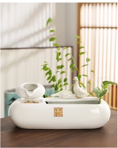 Macro detail of white ceramic tabletop water fountain with swan decor and golden lettering