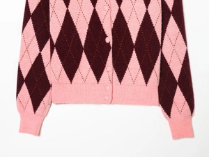 Detailed macro view of the argyle knit cardigan with pink buttons and ribbed hem