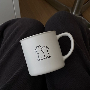 Close-up of white ceramic mug featuring minimalist black cartoon dog illustration