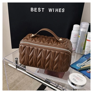 Dettaglio macro della borsa cosmetica in pelle PU marrone con eleganti cuciture a V