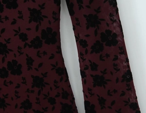 Detail of burgundy mesh fabric with black velvet floral flocking and sheer texture