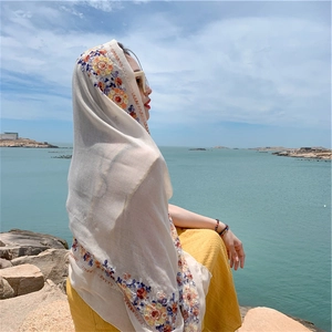 Ethnic style beige scarf with colorful floral embroidery worn by the sea side