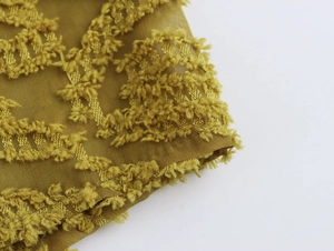 Detailed macro view of mustard yellow lantern sleeve cuff with textured jacquard fabric