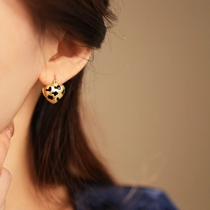 Close-up of a vintage golden heart earring with black leopard print on a model's ear