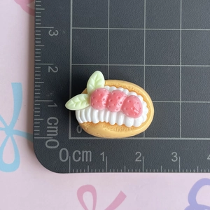 Macro shot of resin strawberry cream cake charm on a measuring mat for size detail