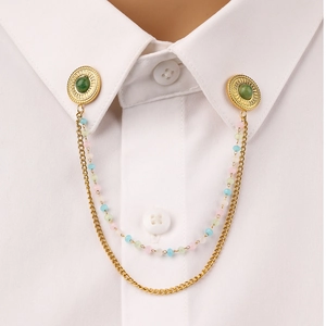 Detail of a gold-tone collar pin chain with green natural stone and colorful beads decor