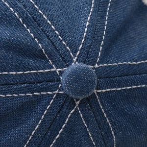 Detailed macro view of the blue denim baseball cap's top with contrast white stitching