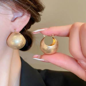 Detailed view of vintage matte gold U-shaped basket hoop earrings on a model and in hand