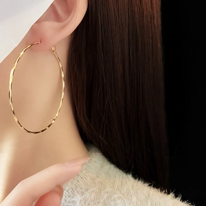 Close-up of golden hammered hoop earring worn by a model with textured metallic finish