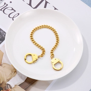 Detailed top view of gold-colored handcuff pendant necklace on a white ceramic plate