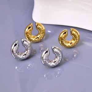 Detail view of gold and silver horseshoe earrings with textured hammer finish texture