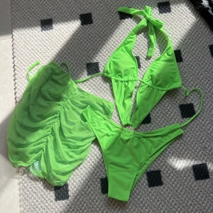 Detailed macro view of a 3-piece neon green bikini set with a mesh skirt and gold ring detail