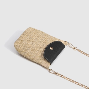 Straw crossbody phone bag with black leather flap and gold chain strap on white background
