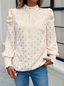 Detail of elegant beige long sleeve blouse with golden polka dots and puffed shoulders