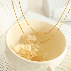 Elegant gold double layered snake bone necklace displayed on a ceramic cup background