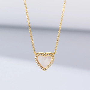 Detailed view of heart-shaped pearl shell necklace with sparkling zircon and gold chain