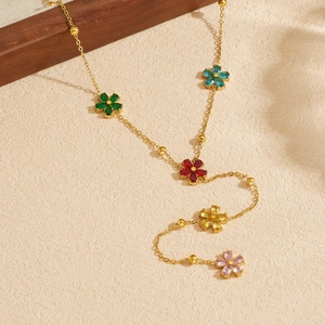 Collier en Y doré avec pendentifs fleurs colorées sur fond texturé beige élégant